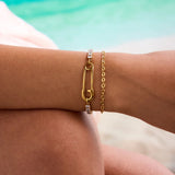 Gold bracelet with a unique design on a person's wrist against a blurred background