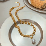Gold chain necklace with a pearl pendant on a white plate
