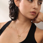 Woman wearing a gold necklace with a delicate pendant against a neutral background