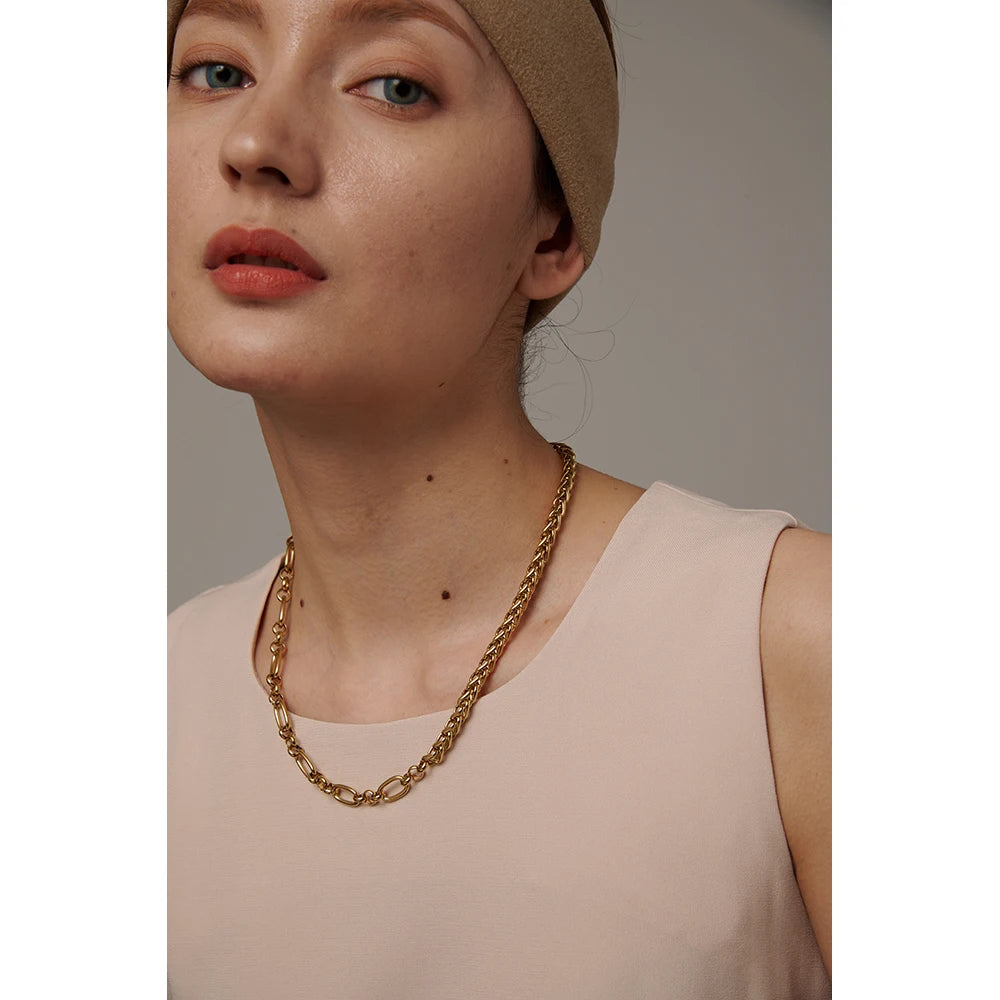 Woman wearing a gold chain necklace with a neutral background