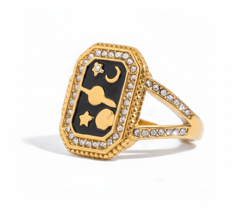 Gold ring with black gemstone and star design on a white background 