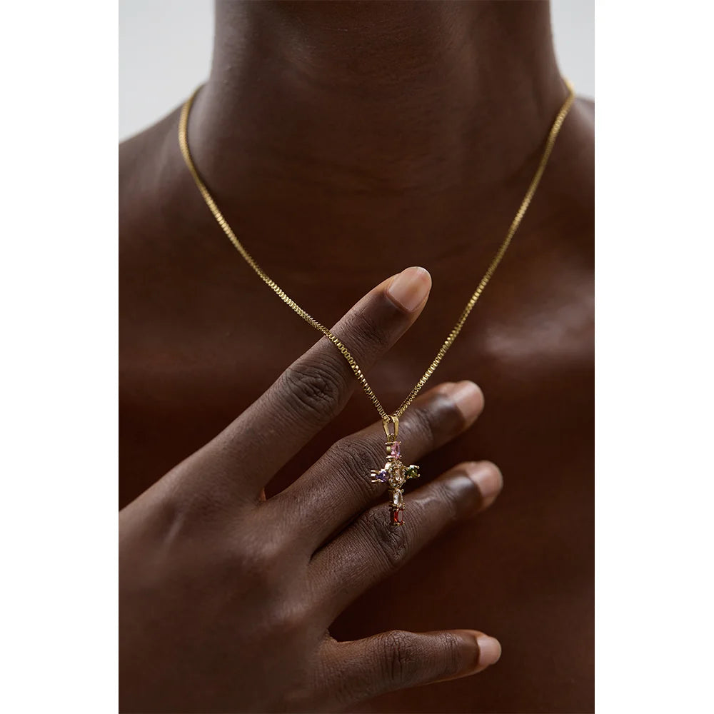 Gold necklace with a cross pendant worn by a person