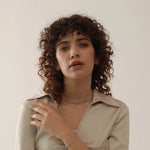 Woman with curly hair wearing a beige shirt against a plain background