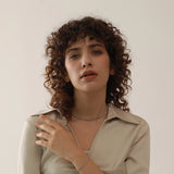 Woman with curly hair wearing a beige shirt against a plain background