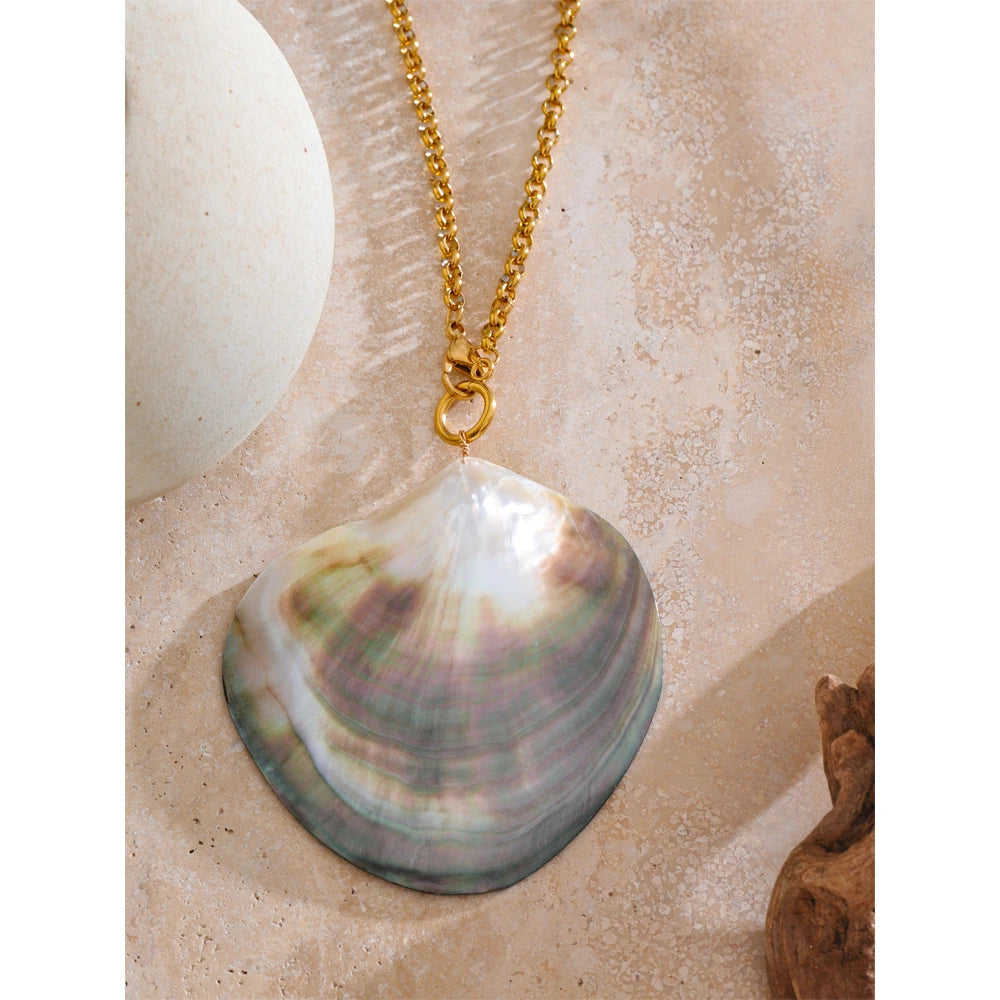 Shell pendant on a gold chain against a beige background