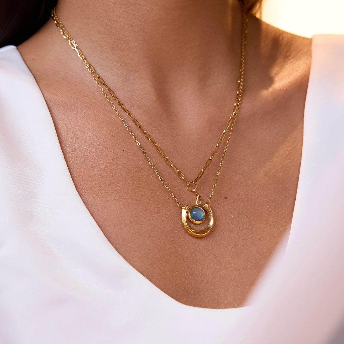 Horseshoe Gold necklace with a blue pendant on a white background