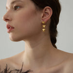 Woman wearing gold heart-shaped earrings with a neutral background