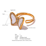 Gold butterfly ring with white center and measurement details on a white background