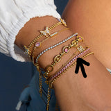 Multiple gold and pink bracelets on a wrist with a blurred background