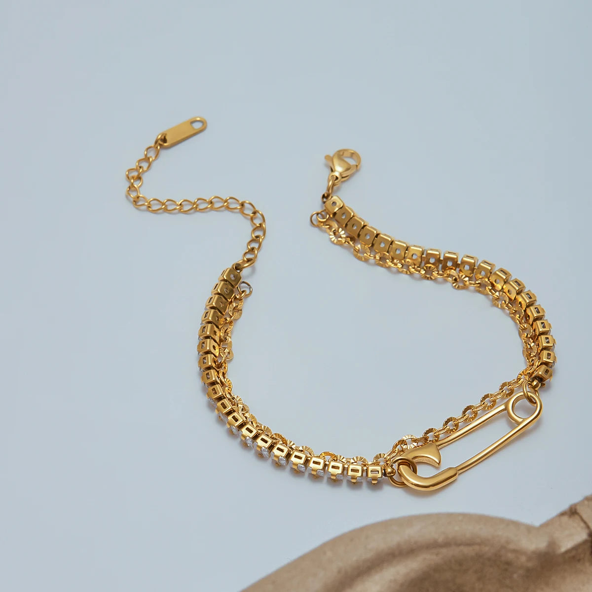 Gold bracelet with a heart clasp on a light blue background