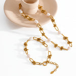 Gold chain necklace with pearls on a textured surface