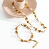 Gold chain necklace with pearls on a textured surface