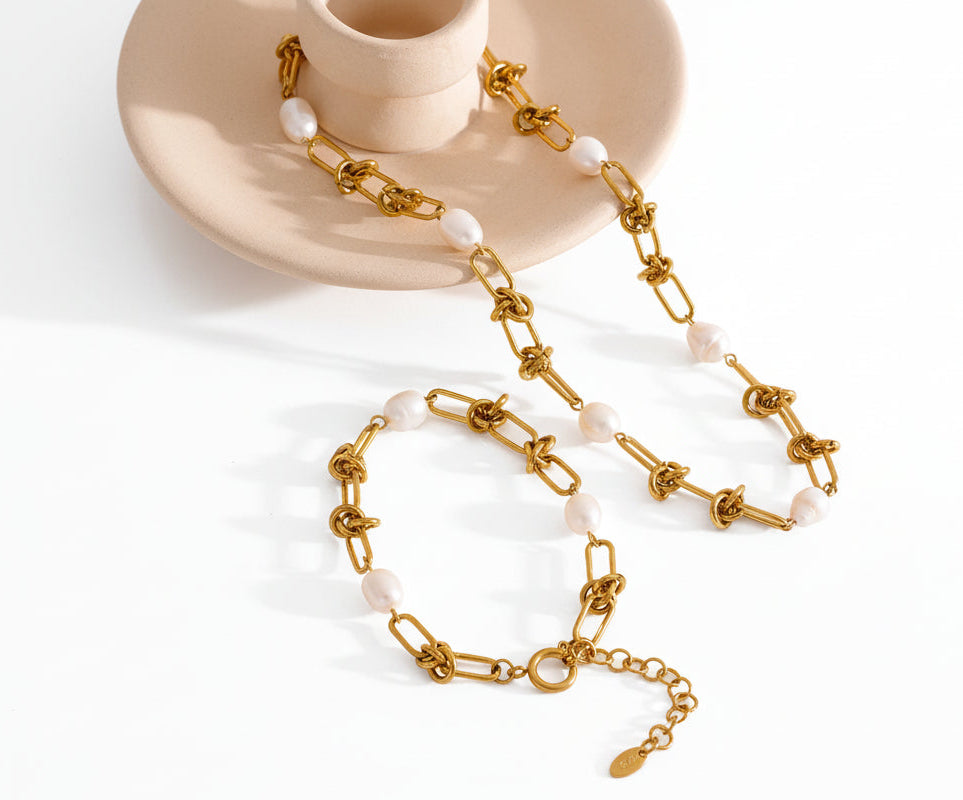 Gold chain necklace with pearls on a textured surface