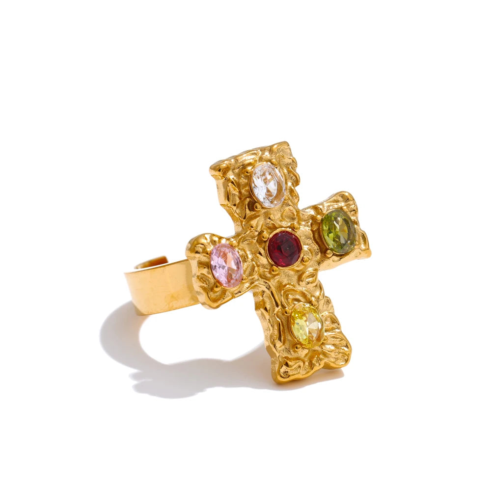 Gold cross-shaped ring with embedded gemstones on a white background