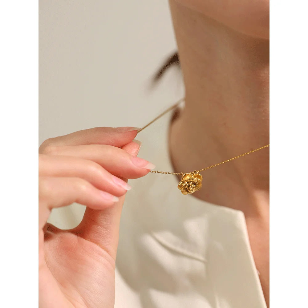 Gold necklace with a rose pendant being worn by a person.