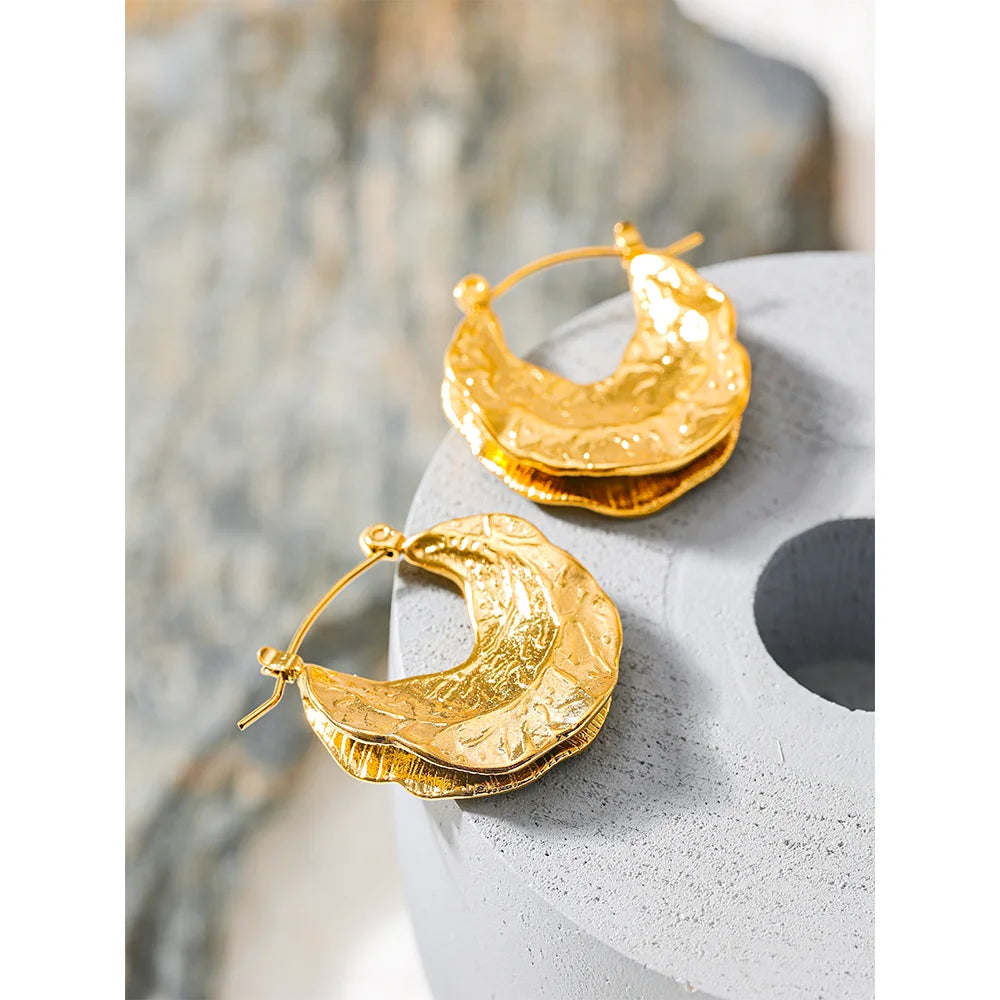Gold hoop earrings on a textured surface