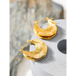 Gold hoop earrings on a textured surface