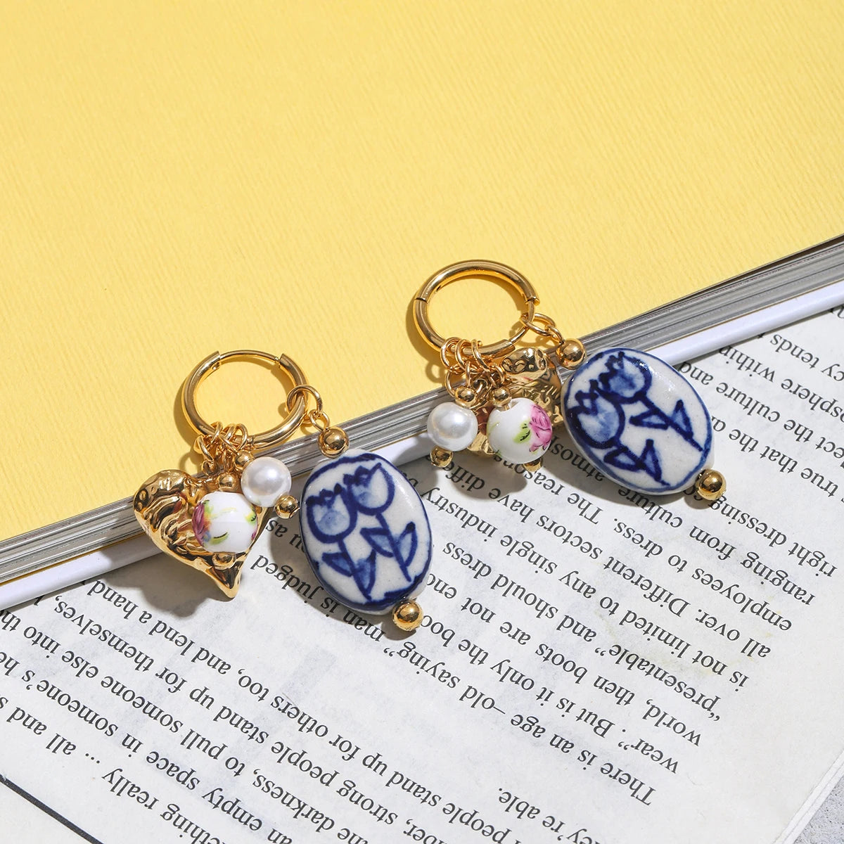 Decorative keychains with floral designs on a book against a yellow background