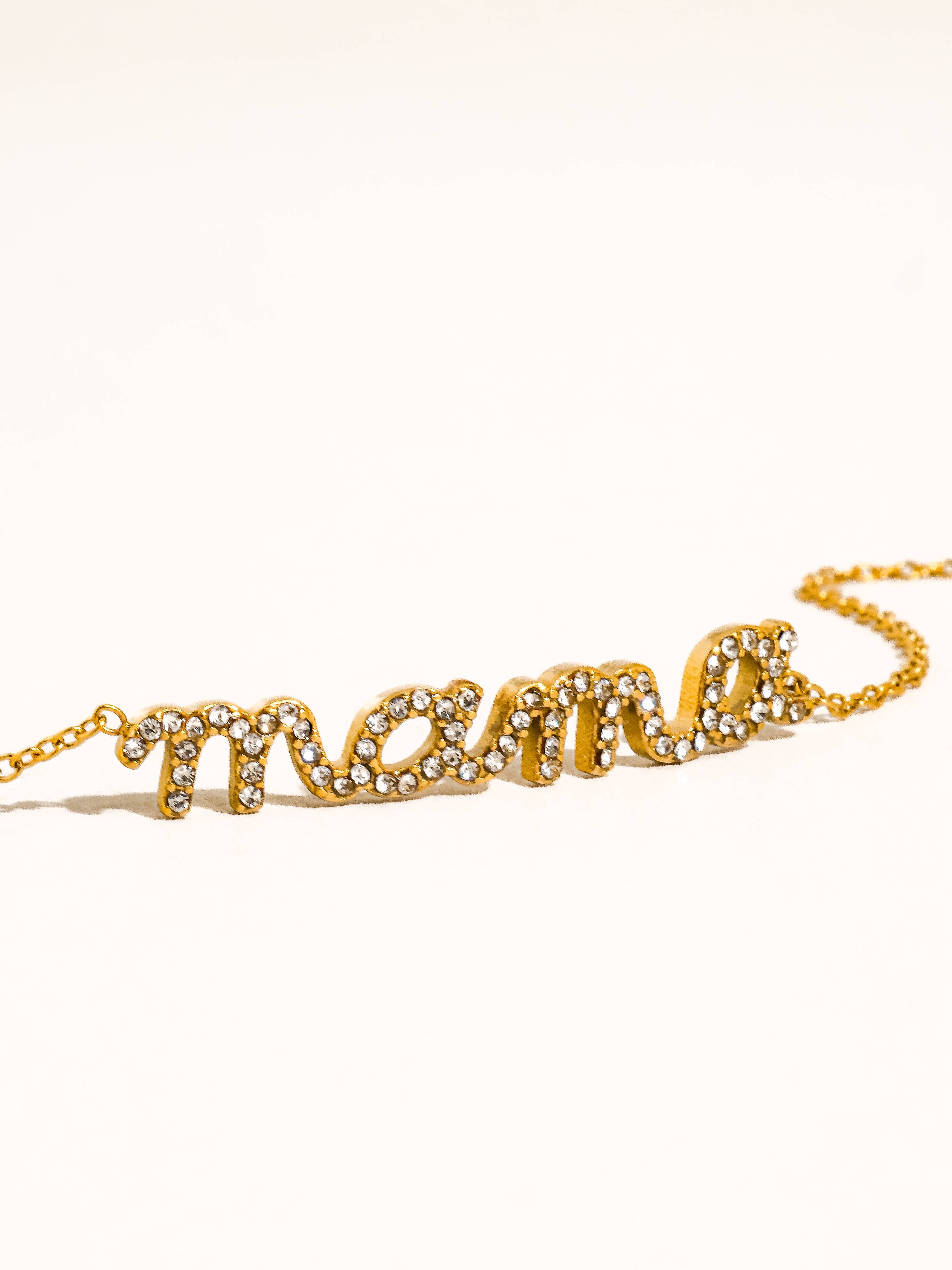 Gold 'mama' necklace with rhinestones on a white background