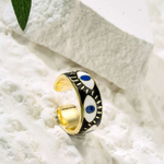 Adjustable evil eye ring with black enamel, gold plating, and blue accents, designed for everyday wear and believed to ward off negative energy.