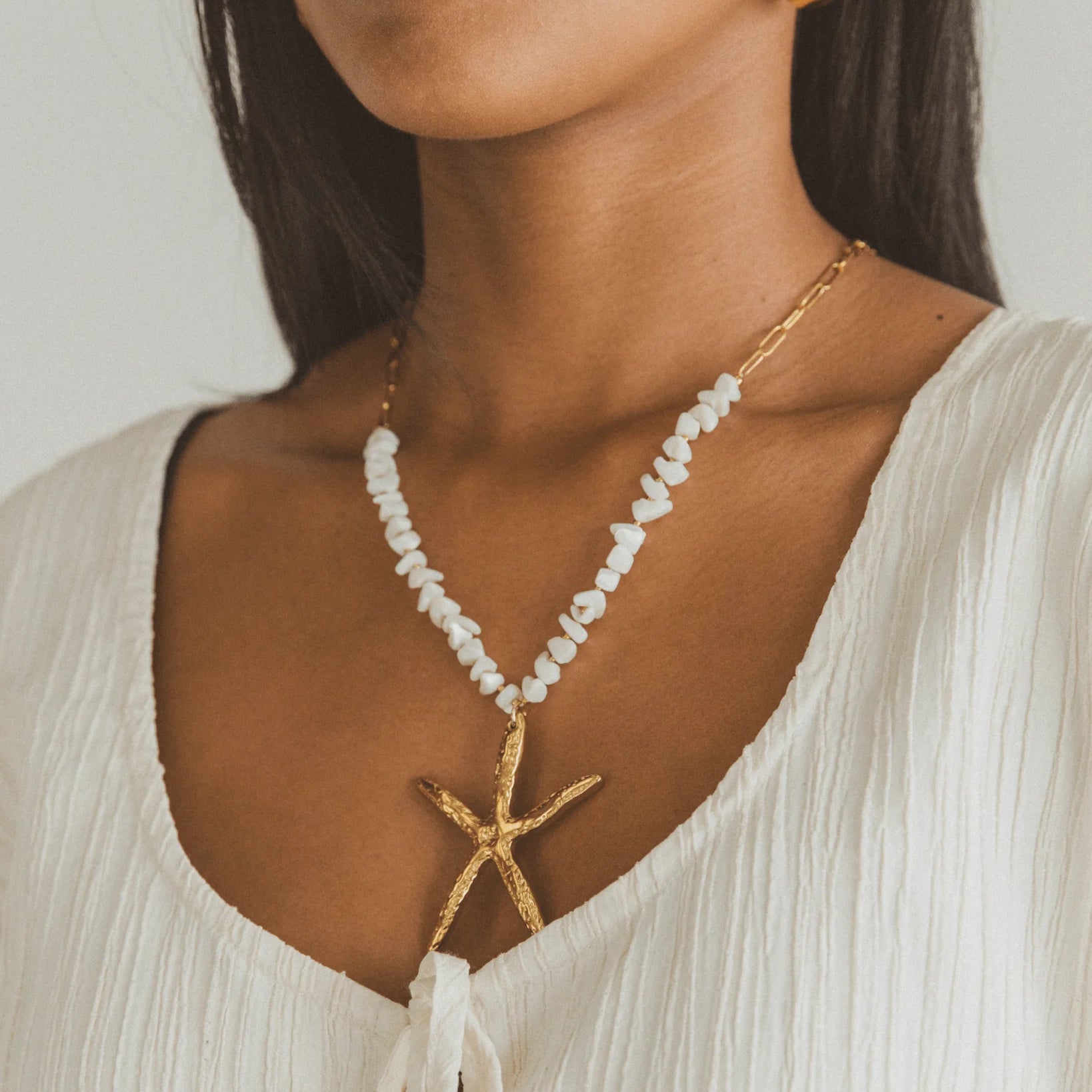 Beach-inspired golden starfish necklace with natural shell bead chain and gold plating, perfect for summer or coastal outfits