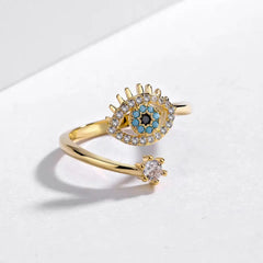 Blue evil eye protection ring with gold-plated band, onyx, turquoise, and zirconia stones, adjustable and symbolic of good energy.