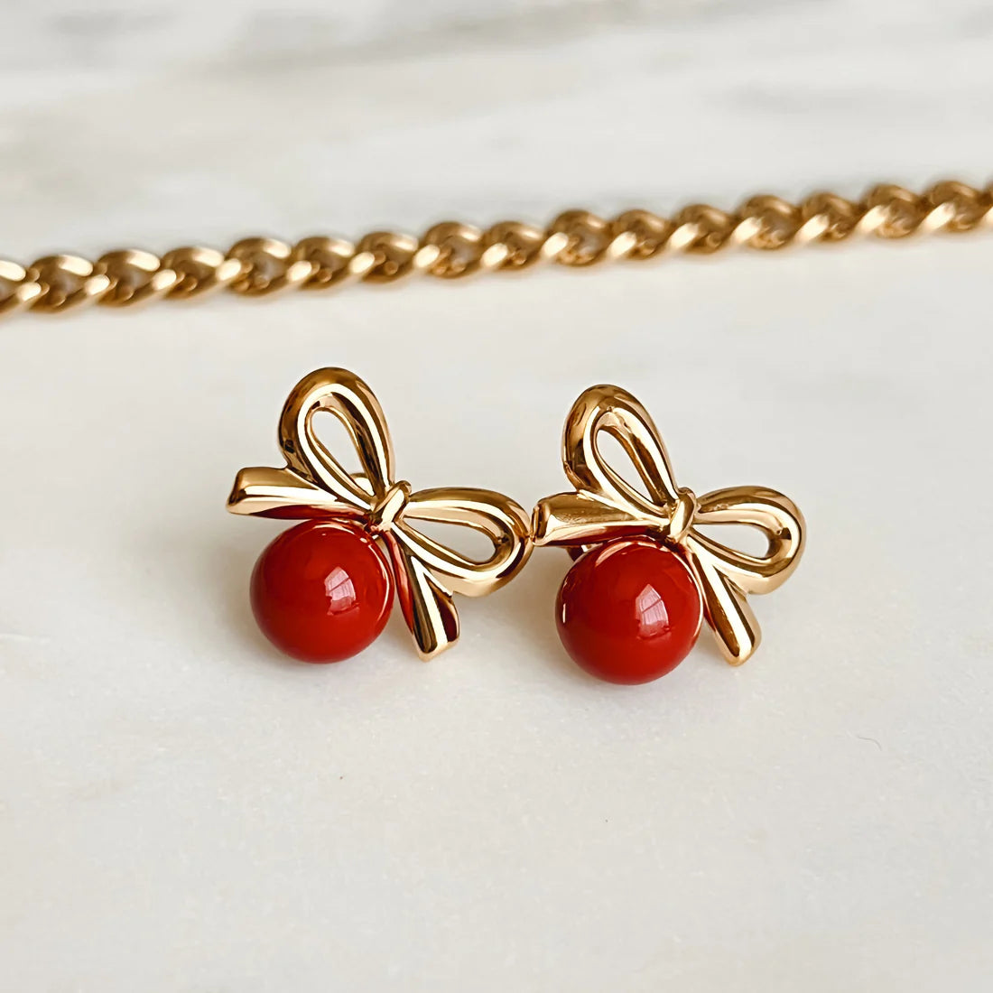Elegant Cherry Red Bow Earring, 18K gold-plated with a smooth red stone and detailed gold bow for a unique, playful style.