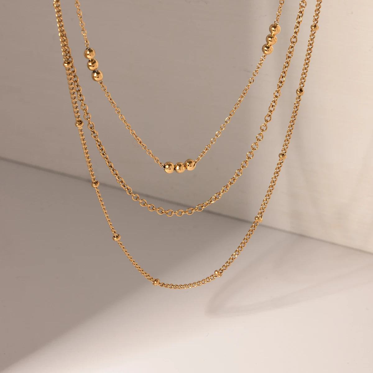 Delicate Beaded Gold Layered Necklace, 18K gold-plated with three tiered chains and polished beads, perfect for an elegant, cascading style.
