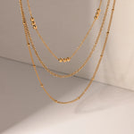 Delicate Beaded Gold Layered Necklace, 18K gold-plated with three tiered chains and polished beads, perfect for an elegant, cascading style.