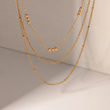 Delicate Beaded Gold Layered Necklace, 18K gold-plated with three tiered chains and polished beads, perfect for an elegant, cascading style.