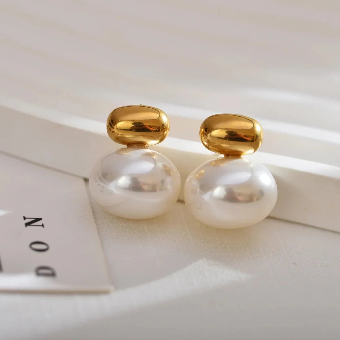 Elegant Double Pearl Gold Stud Earrings, 18K gold-plated with a large white pearl and sleek gold cap, perfect for any occasion.