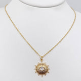 Protective evil eye sunburst pendant necklace for women with a shimmering cubic zirconia in a gold-plated setting.