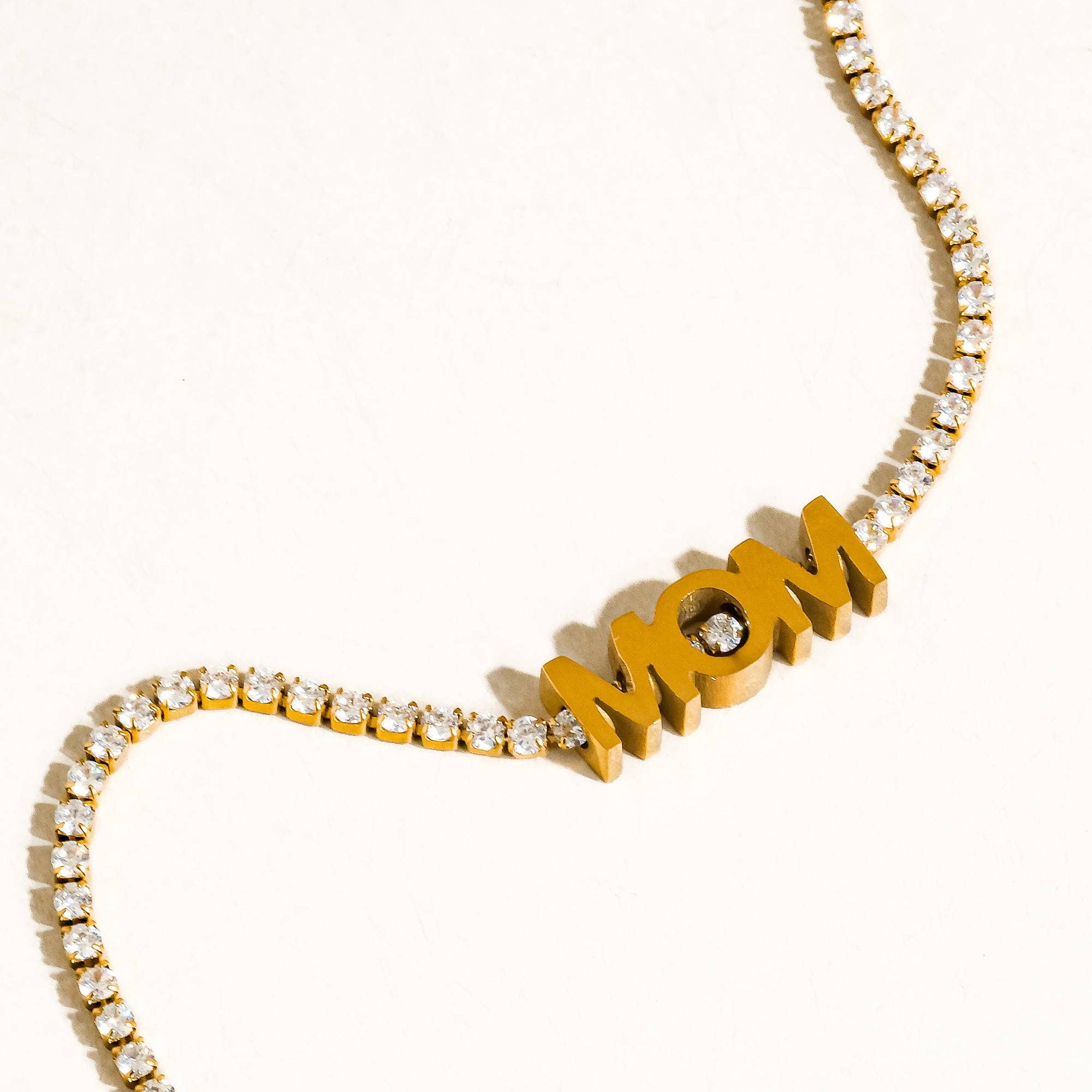 Gold necklace with 'MOM' pendant on a white background