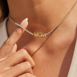 Gold 'MOM' necklace being worn on a person's neck with a close-up of the necklace.