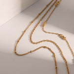 Stylish Gold Beaded Layered Necklace, 18K gold-plated with three delicate chains and polished gold beads, adding elegance to any look.