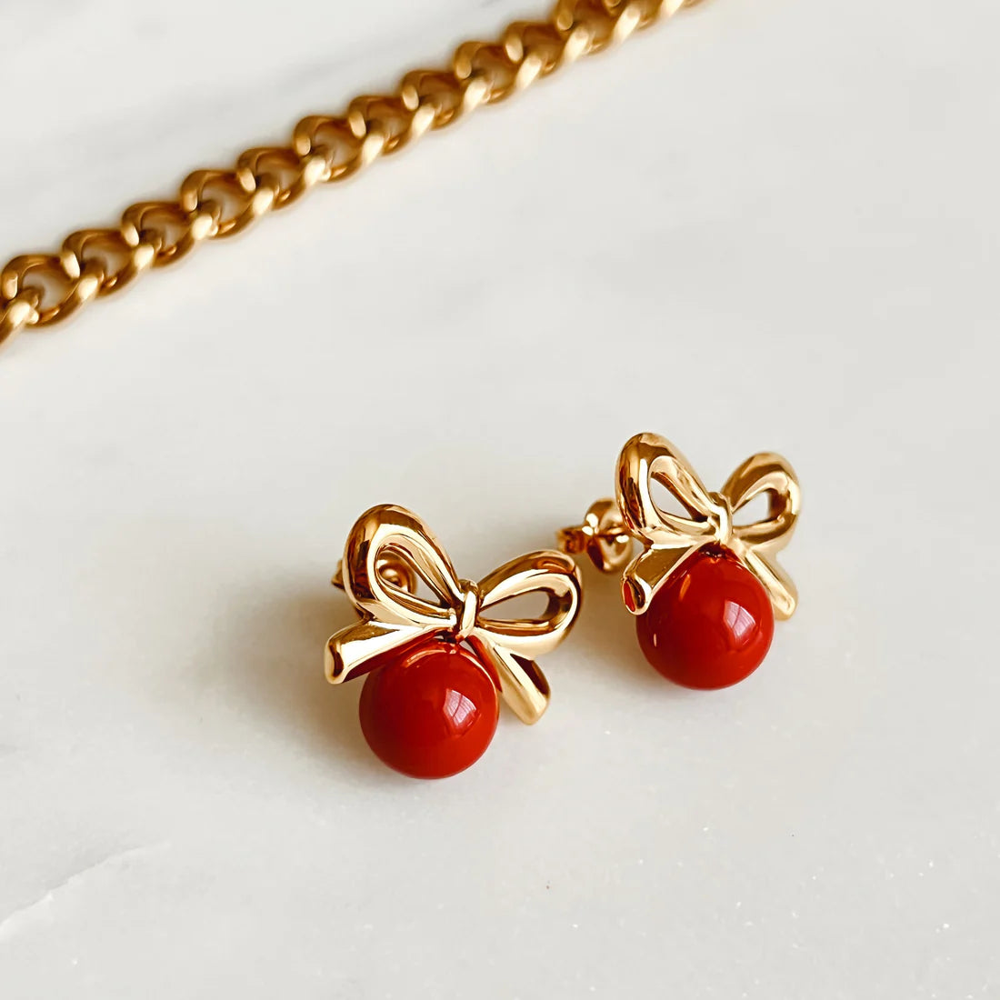 Charming Gold Bow Cherry Earring with a glossy red stone, 18K gold-plated, offering a playful yet elegant touch to any outfit.