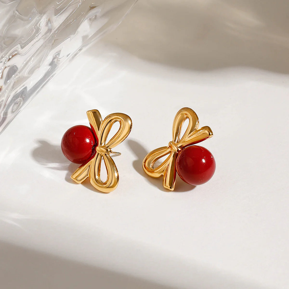 Playful Gold Cherry Bow Earring with a glossy red stone, 18K gold-plated, adding a charming and elegant touch to your look.