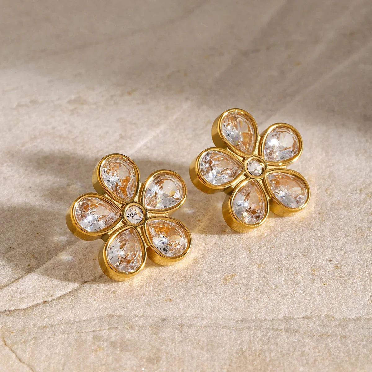 Daisy-inspired gold flower stud earrings featuring crystal accents and a shimmering diamond-cut finish
