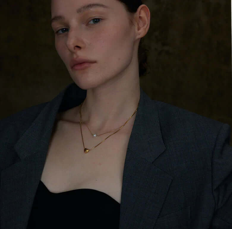 Elegant 18k gold layered necklace featuring a pearl and dainty heart charm, perfect for adding romance to any outfit

