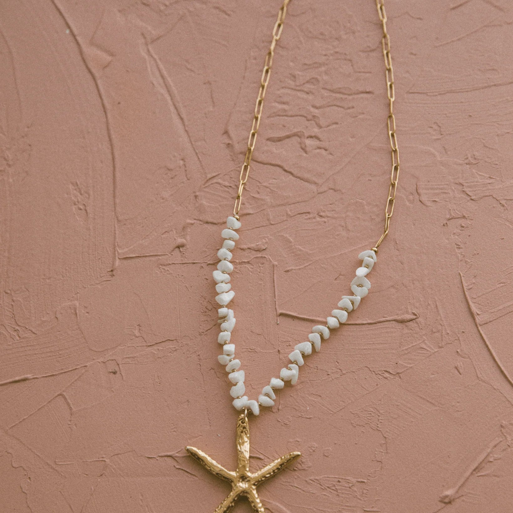 Gold starfish charm necklace with textured finish and shell beads, ideal for ocean lovers and relaxed summer style