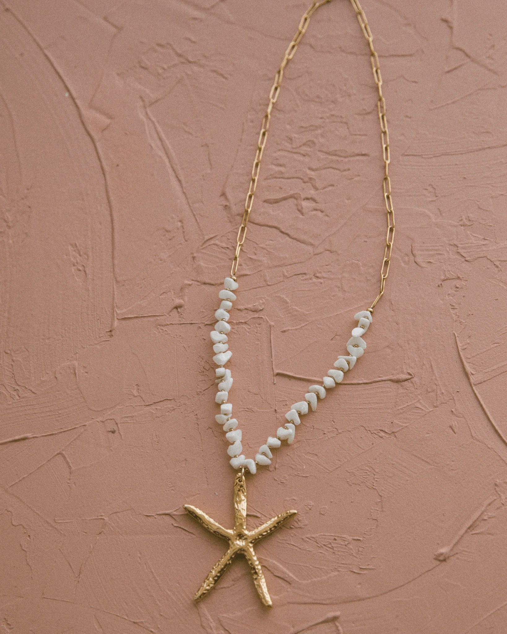 Gold starfish charm necklace with textured finish and shell beads, ideal for ocean lovers and relaxed summer style