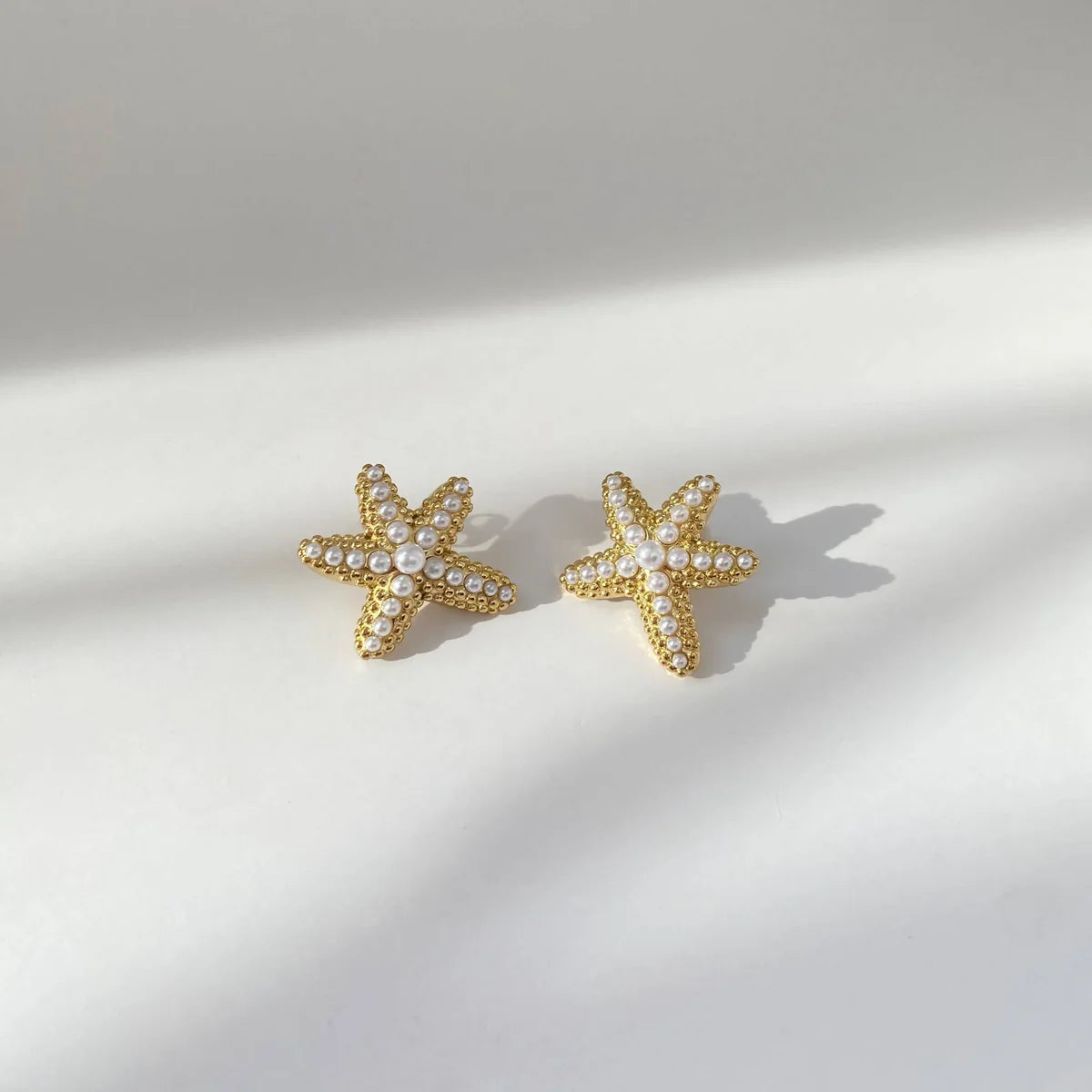Gold starfish earrings with pearl tops, offering a stylish ocean-inspired accessory for everyday wear or vacations