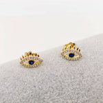 Golden evil eye stud earrings with deep blue center and sparkling cubic zirconia, 18k gold plated on stainless steel, stylish protective everyday jewelry.