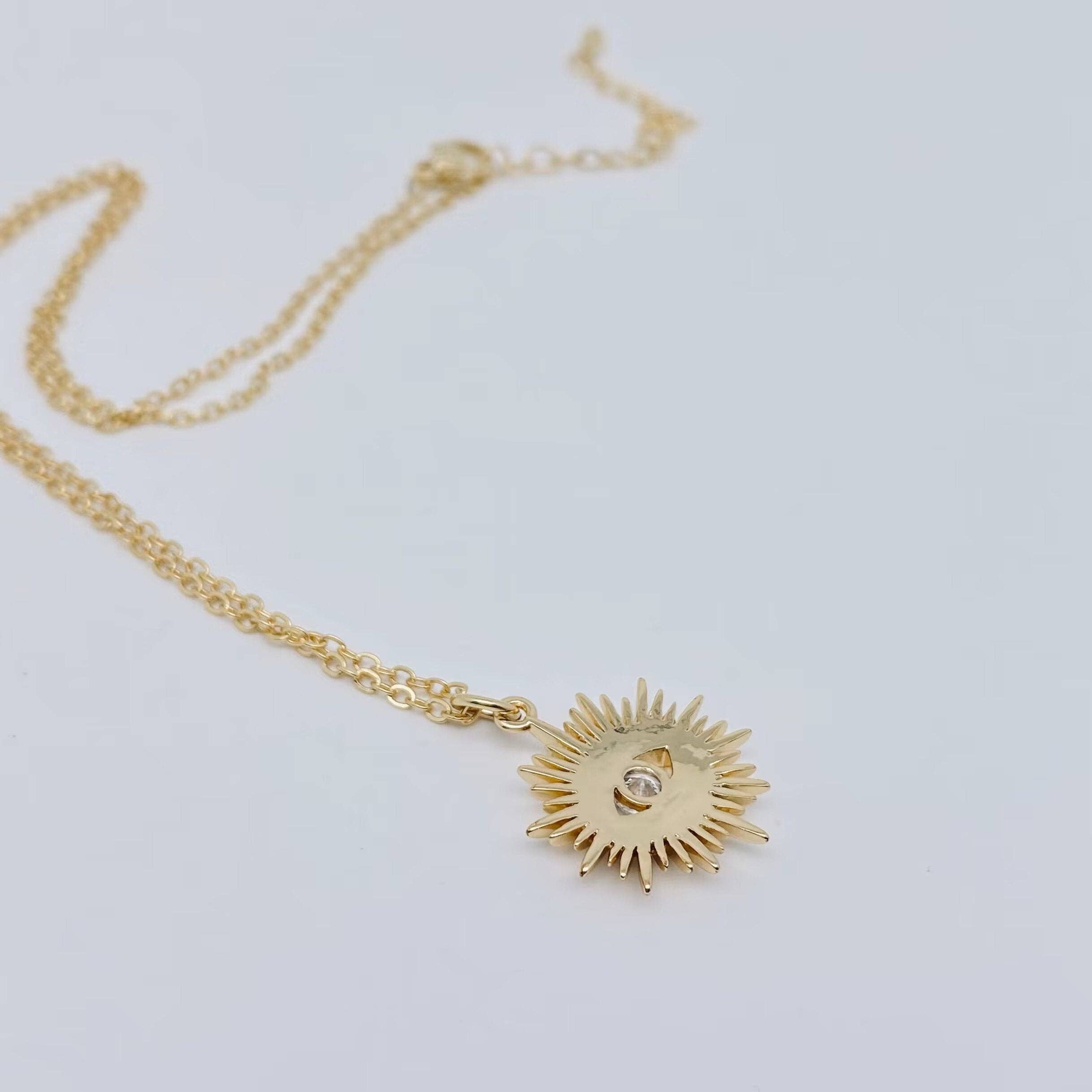 Layer-friendly sunburst evil eye pendant in gold, featuring a radiant charm and sparkling eye detail.

