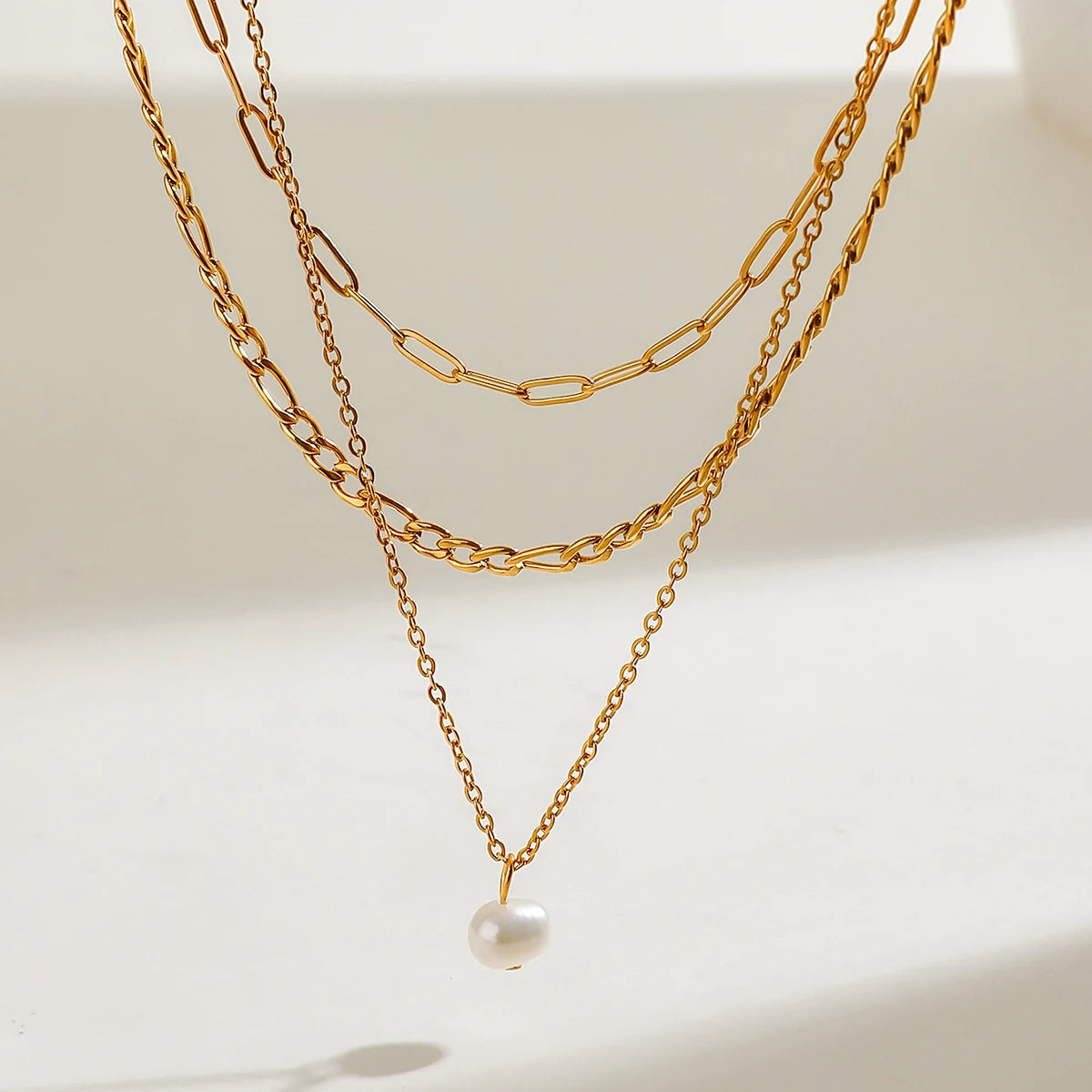Delicate Triple Chain Necklace with a Natural Pearl Drop, 18K gold-plated, designed to add elegance and shine to any outfit.