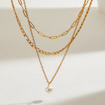 Delicate Triple Chain Necklace with a Natural Pearl Drop, 18K gold-plated, designed to add elegance and shine to any outfit.
