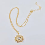 Gold-plated sunburst evil eye pendant necklace with cubic zirconia center, offering stylish protection and elegance for everyday wear.